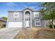 Two-story house with gray exterior, arched entryway, and white garage door at 1703 Alhambra Crest Dr, Ruskin, FL 33570