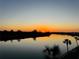 Stunning sunset over calm water with palm trees in foreground at 18325 Gulf Blvd # 405, Redington Shores, FL 33708