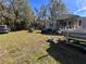 Front yard of mobile home with vehicles and debris at 26418 Dayflower Blvd, Wesley Chapel, FL 33544