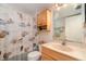 Clean bathroom with light wood cabinets and a seashell-themed shower curtain at 2700 Magdalina Dr # 2B, Punta Gorda, FL 33950
