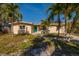 Tan single story home with teal door and palm trees at 8349 41St N Ave, St Petersburg, FL 33709