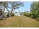 Spacious backyard with lush grass and mature trees, plus a glimpse of the pool at 1061 Sedeeva St, Clearwater, FL 33755