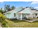 Charming light teal home with covered porch and well-manicured lawn at 1061 Sedeeva St, Clearwater, FL 33755