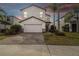 Inviting two-story home with a well-manicured lawn, brick driveway, and a two-car garage at 12408 Victarra Pl, New Port Richey, FL 34655