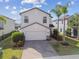 Beautiful two-story home featuring a brick driveway, a two-car garage, and a green lawn with palm trees at 12408 Victarra Pl, New Port Richey, FL 34655