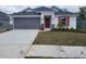 New home exterior featuring gray siding, red shutters, and a two-car garage at 13154 Kent Bradley Glade Rd, Dade City, FL 33525