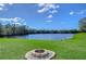 Picturesque lake view from a lush green backyard featuring a charming fire pit area for relaxation and gatherings at 13908 Orange Dale Pl, Tampa, FL 33625