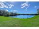 Scenic view of a serene lake surrounded by lush greenery and a clear blue sky with scattered clouds at 13908 Orange Dale Pl, Tampa, FL 33625