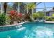 Tranquil backyard pool with a small waterfall feature, lush landscaping, and privacy screen at 15110 Shearcrest Dr, Lithia, FL 33547