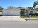 Charming yellow single-story home with well-manicured landscaping, three-car garage and ample driveway space at 16103 Muirfield Dr, Odessa, FL 33556