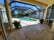 Inviting screened-in pool area with a hot tub, complemented by lush greenery and travertine tiled deck at 16103 Muirfield Dr, Odessa, FL 33556