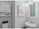 Small powder room with a pedestal sink and decorative flamingo art at 16317 Gulf Blvd, Redington Beach, FL 33708