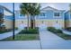 Charming townhome featuring a blue and yellow exterior, with a well-maintained lawn and palm trees at 1708 Sunset Wind Loop, Oldsmar, FL 34677