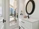 Elegant bathroom with white vanity, black hardware, oval mirror and natural light from the patio at 17336 Ballmont Park Dr, Odessa, FL 33556