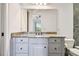 Bathroom vanity with granite countertop, white cabinetry and large mirror reflecting the bright bedroom at 17336 Ballmont Park Dr, Odessa, FL 33556