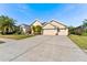 Tan house with three-car garage and large driveway at 26853 Winged Elm Dr, Wesley Chapel, FL 33544