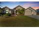 Stunning tan house with three-car garage and beautiful landscaping at dusk at 26853 Winged Elm Dr, Wesley Chapel, FL 33544