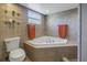 Cozy bathroom featuring a corner bathtub, toilet, and neutral-toned tile at 540 Villagrande S Ave, St Petersburg, FL 33707