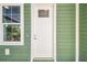 Charming front door with window pane, complimented by a bright window and green siding at 5644 Missouri Ave, New Port Richey, FL 34652