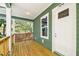 Inviting front porch featuring wood floors, green siding, and a charming white front door and window at 5644 Missouri Ave, New Port Richey, FL 34652