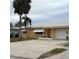 One-story house with a white roof, attached garage, and palm trees at 1019 Mandalay Ave, Clearwater Beach, FL 33767