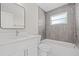 Modern bathroom with white vanity, gray tile, and a bathtub at 11395 83Rd Ave, Seminole, FL 33772