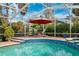 Enjoy dining al fresco in this screened pool area with red umbrella at 15927 Ternglade Dr, Lithia, FL 33547