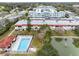 Aerial view showcasing condo building, pool, pond, and surrounding greenery at 1750 Belleair Forest Dr # A15, Belleair, FL 33756