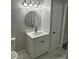 Bathroom features a white vanity with a speckled countertop, a round mirror, and modern lighting fixture at 1804 Cadillac Cir, Tampa, FL 33619