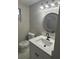 This bathroom features a white vanity with a speckled countertop, a round mirror, and modern lighting fixture at 1804 Cadillac Cir, Tampa, FL 33619