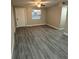 Bright, freshly painted living room with new ceiling fan and light-filled window, showcasing modern gray wood-look flooring at 1804 Cadillac Cir, Tampa, FL 33619