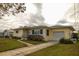 Ranch-style home with a yellow exterior, attached garage, and landscaped lawn at 1900 41St N St, St Petersburg, FL 33713