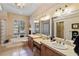 Spacious bathroom featuring dual sinks, a soaking tub, decorative lighting, and neutral tile throughout at 2987 Wentworth Way, Tarpon Springs, FL 34688