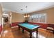 A game room with a pool table, wooden floors, and plantation shutters at 2987 Wentworth Way, Tarpon Springs, FL 34688