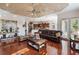 Open living room with a brown leather sofa, hardwood floors, tray ceiling and an open view of the kitchen at 2987 Wentworth Way, Tarpon Springs, FL 34688