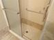 Bathroom shower with grab bar, tiled floor, showerhead, and glass doors at 3300 Cove Cay Dr # 6G, Clearwater, FL 33760