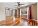 Bedroom with wood floors, ceiling fan, large windows with red curtains and mirrored closet doors at 3903 Sand Dollar Pl, Tampa, FL 33634