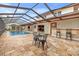 A covered patio features an outdoor kitchen, bar, travertine floors, and a screened-in pool for relaxing or entertaining at 3903 Sand Dollar Pl, Tampa, FL 33634