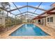 Lovely screened pool with stone tile surround, lush landscaping, and view into the home at 3903 Sand Dollar Pl, Tampa, FL 33634