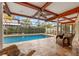 Screened outdoor pool area featuring tiled patio, ceiling fan, wood beams and comfortable patio furniture at 3903 Sand Dollar Pl, Tampa, FL 33634