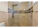 Shower with glass door and travertine tile walls with decorative band at 3903 Sand Dollar Pl, Tampa, FL 33634