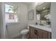 Clean bathroom with wood vanity, white toilet, and a window with curtains at 409 E Adalee St, Tampa, FL 33603