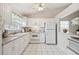 White kitchen featuring a double sink, matching appliances, and sleek tile floors at 4210 Revere Cir, New Port Richey, FL 34653