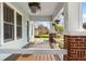 Cozy front porch featuring brick columns, a wooden deck, and hanging flower baskets at 705 W Kentucky Ave, Tampa, FL 33603