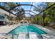 Inviting screened-in pool area with sun loungers, patio seating, and lush tropical landscaping at 705 W Kentucky Ave, Tampa, FL 33603