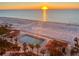 Aerial view of a community pool area at sunrise with palm trees and beach access at 880 Mandalay Ave # N111, Clearwater Beach, FL 33767