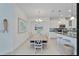 Dining room with a long wooden table, seating for six, and views into the modern, white kitchen at 970 Pembroke Point Way, Sun City Center, FL 33573