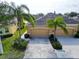 Tan house with large driveway and two palm trees in front of a large multi-car garage at 970 Pembroke Point Way, Sun City Center, FL 33573