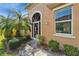 Charming front entrance with a decorative door, palm tree, and well-maintained landscaping at 970 Pembroke Point Way, Sun City Center, FL 33573