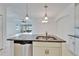 Kitchen island with granite countertops, stainless steel sink, white cabinets, and open view to the living areas at 970 Pembroke Point Way, Sun City Center, FL 33573